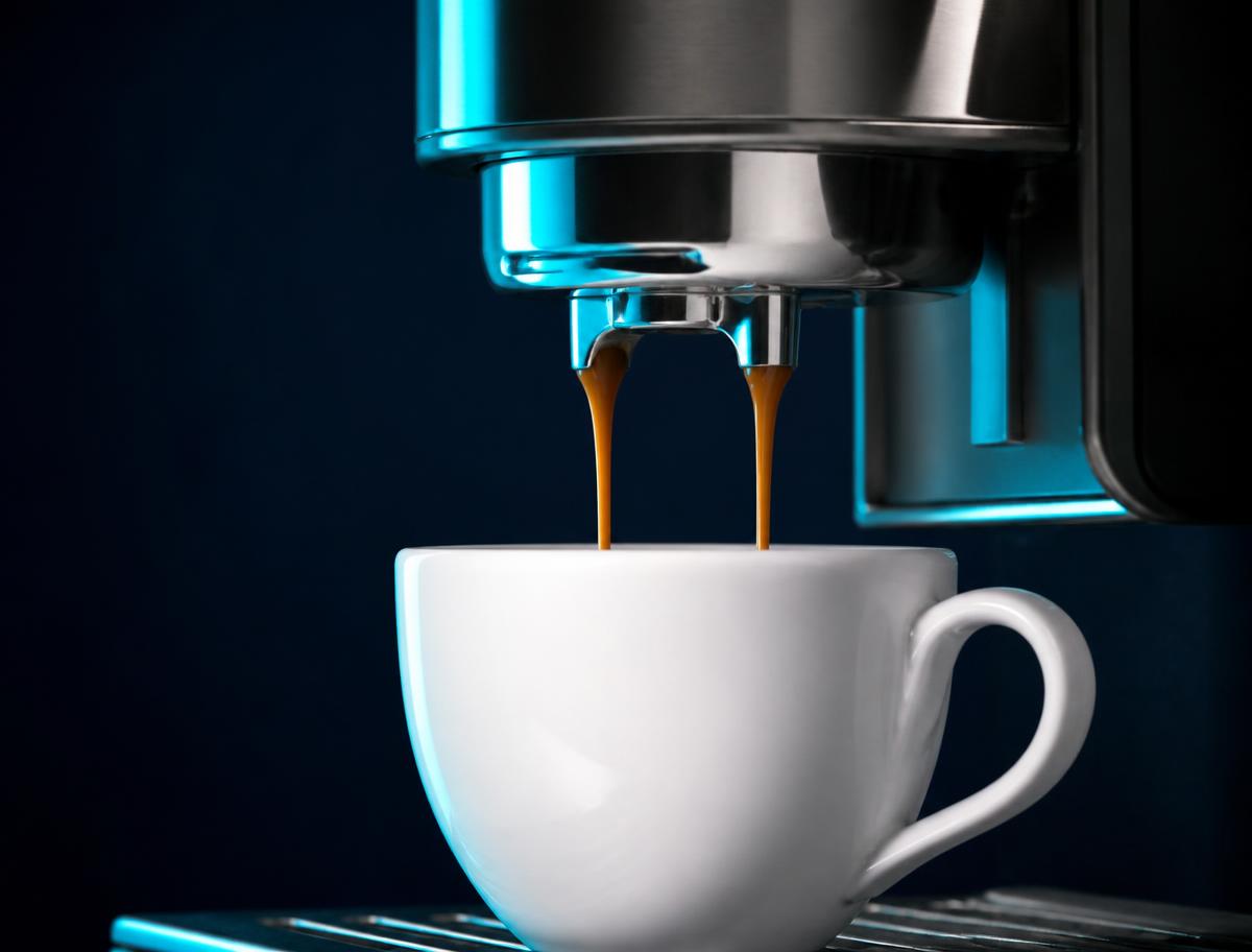 Espresso pouring from a bean-to-cup coffee machine into a white cup